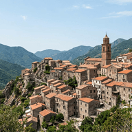 freepik_a-wide-shot-captures-a-picturesque-italian-village-nestled-precariously-on-a-steep-rocky-mountainside-the-village-is-characterized-by-its-densely-packed-terracottaroofed-houses-with-ston_0001