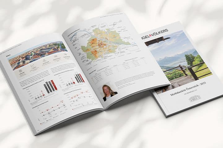 Aufgeschlagenes Marktbericht-Heft mit Diagrammen, Karten und Texten, daneben das Deckblatt mit Landschaftsfoto und der Aufschrift „Marktbericht Österreich 2023“ von Engel & Völkers, auf hellem Untergrund mit weichen Schattenspielen.