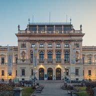 Neoklassizistisches Universitätsgebäude mit verzierter Steinfassade, Statuen entlang der Dachlinie, Bogenfenstern und Schriftbändern