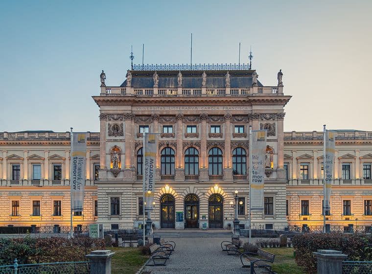 Neoklassizistisches Universitätsgebäude mit verzierter Steinfassade, Statuen entlang der Dachlinie, Bogenfenstern und Schriftbändern