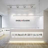Helles, modernes Engel & Völkers Büro mit weißen Wänden, hellen Holzböden und einem eleganten Empfangstresen mit Immobilienangeboten.