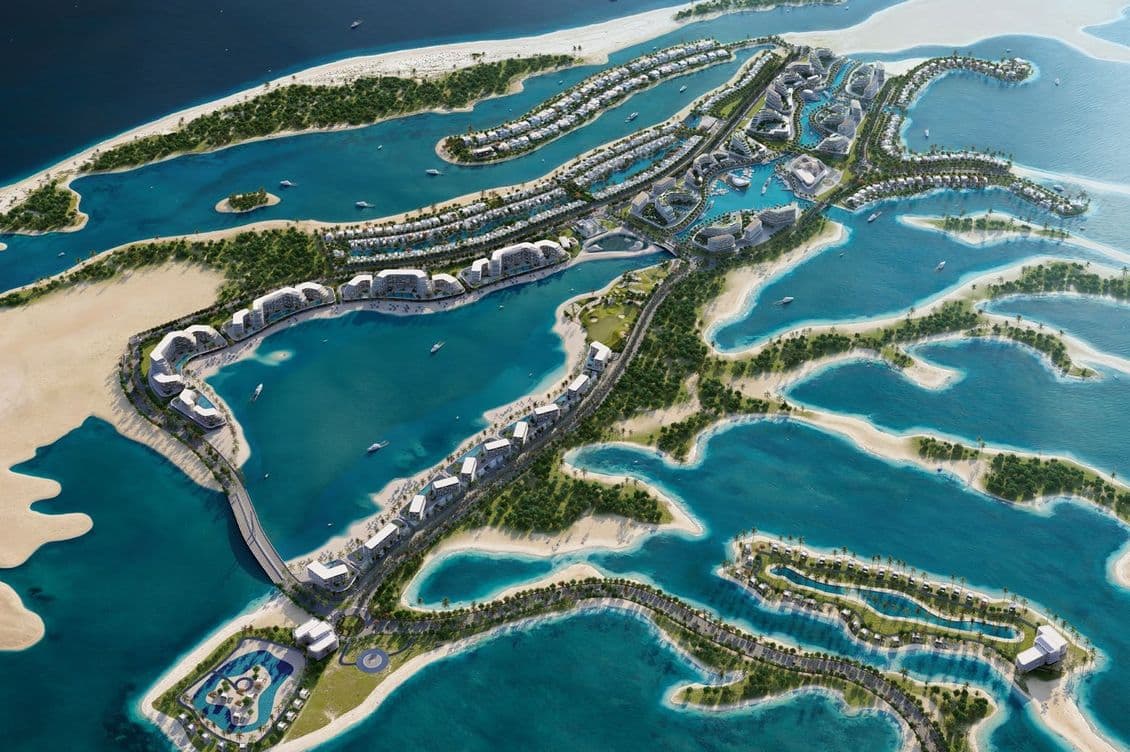 Aerial view of a luxurious island resort with villas, pools, and lush greenery surrounded by blue ocean water.