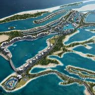 Aerial view of a luxurious island resort with villas, pools, and lush greenery surrounded by blue ocean water.