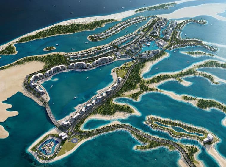 Aerial view of a luxurious island resort with villas, pools, and lush greenery surrounded by blue ocean water.