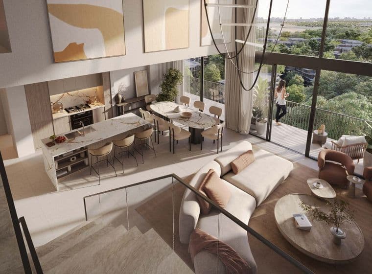 Woman standing on balcony of duplex apartment at Distrikt, overlooking greenery in the Ghaf Woods community.