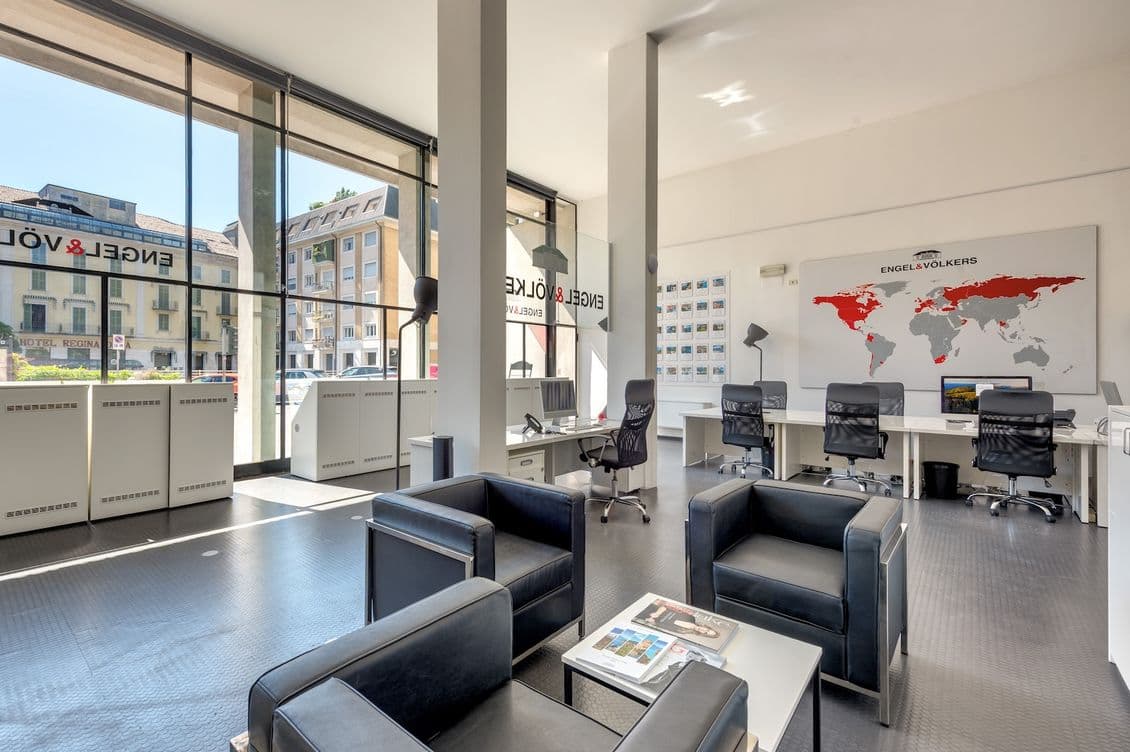 Bright modern office of Lake Como lobby with black leather seating, glass walls, desks and chairs, and a world map on the wall.