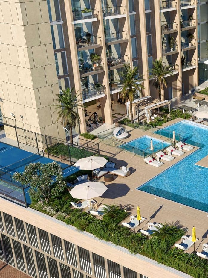 Elevated outdoor leisure deck at Taiyo Residences with a large swimming pool, sun loungers, shaded cabanas, landscaped greenery, and a padel court.