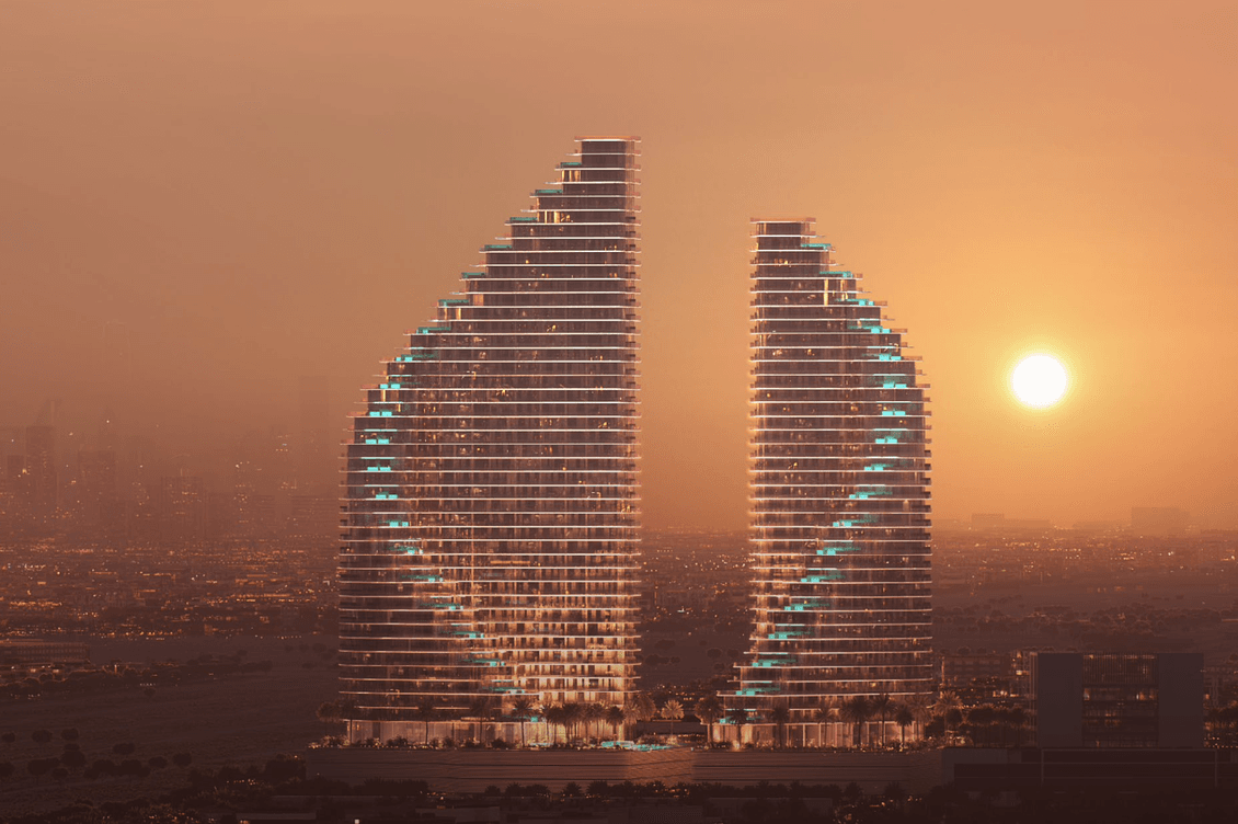 Two sail-shaped skyscrapers at sunset, with glowing lights and a hazy cityscape in the background.