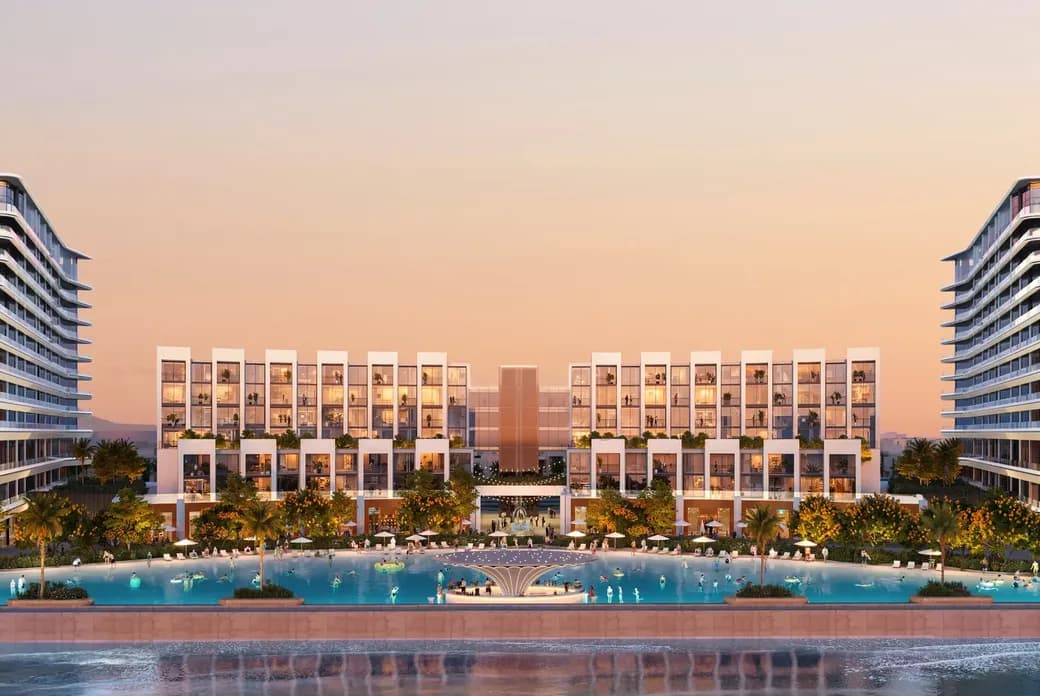 Modern beachfront resort at sunset, featuring symmetrical architecture, lush landscaping, and a tranquil pool reflecting the sky.