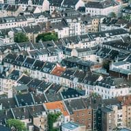 Luftaufnahme von dicht gedrängten europäischen Stadthäusern mit abwechslungsreichen Dächern und einer Mischung aus moderner und traditioneller Architektur.