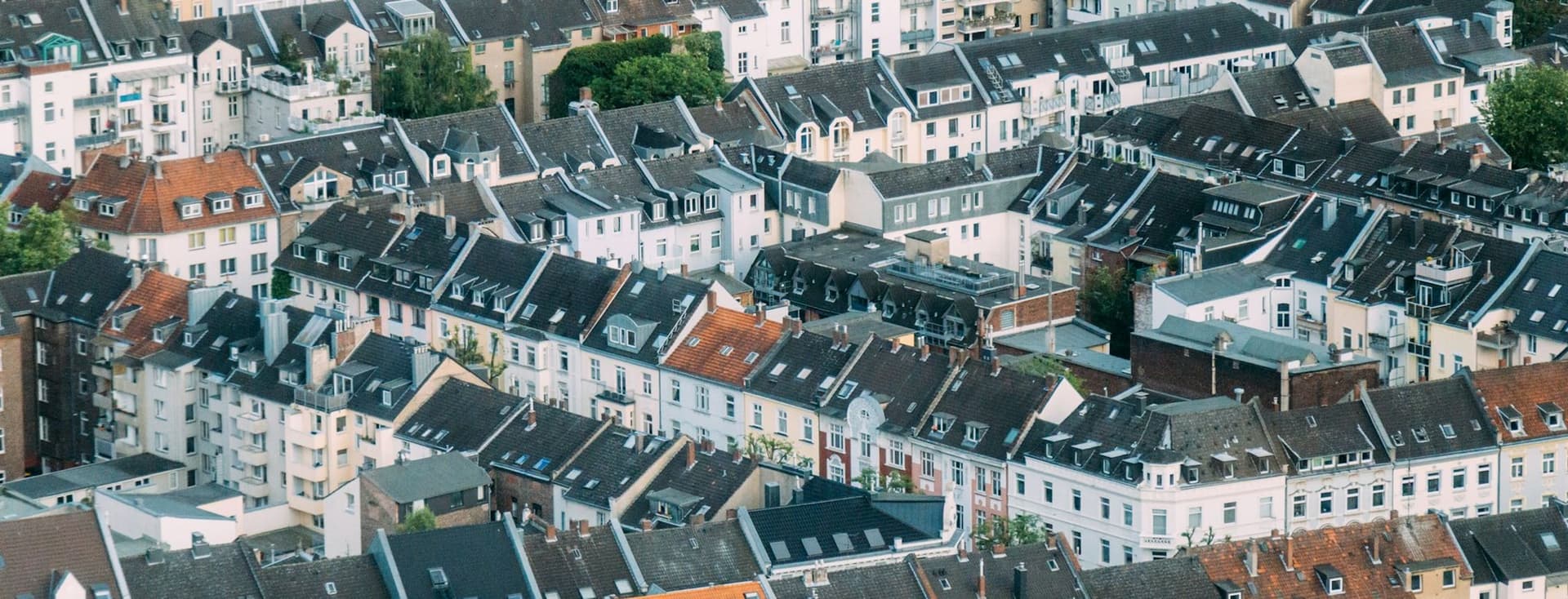 Aerial view of densely packed European townhouses with varied rooftops and a mix of modern and traditional architecture.