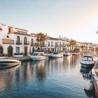 Canal vorejat de cases d’estil espanyol amb balcons de ferro forjat i teulades de terracota, vaixells de luxe amarrats al llarg del passeig marítim.