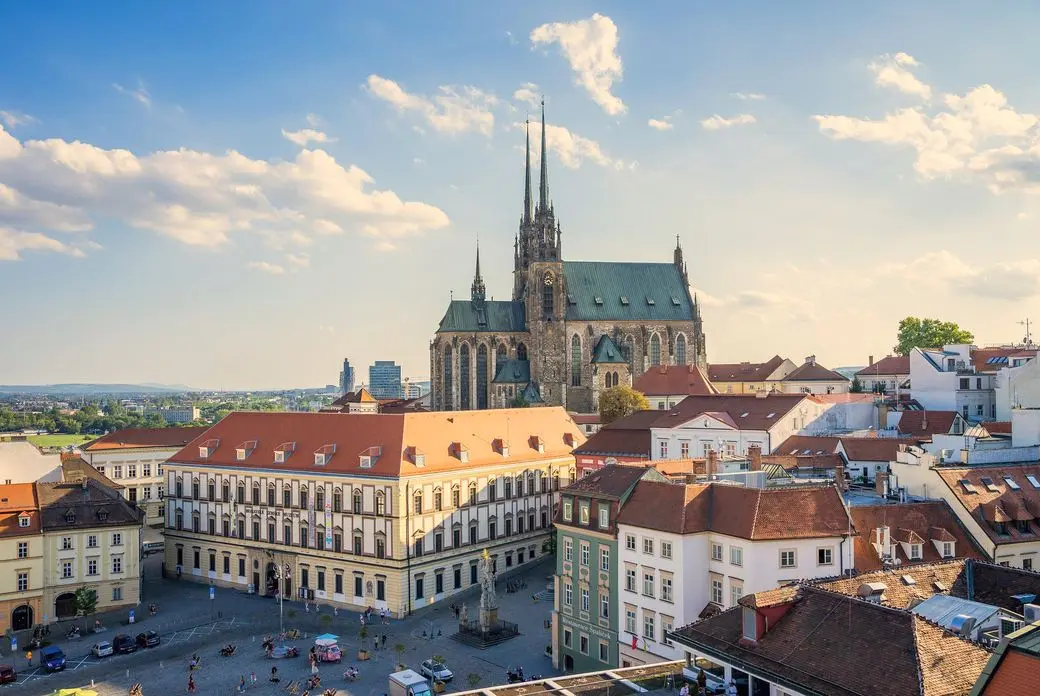 Panoramic view of Brno’s historic centre with red-roofed buildings and the prominent Cathedral of St. Peter and Paul beneath a blue sky.