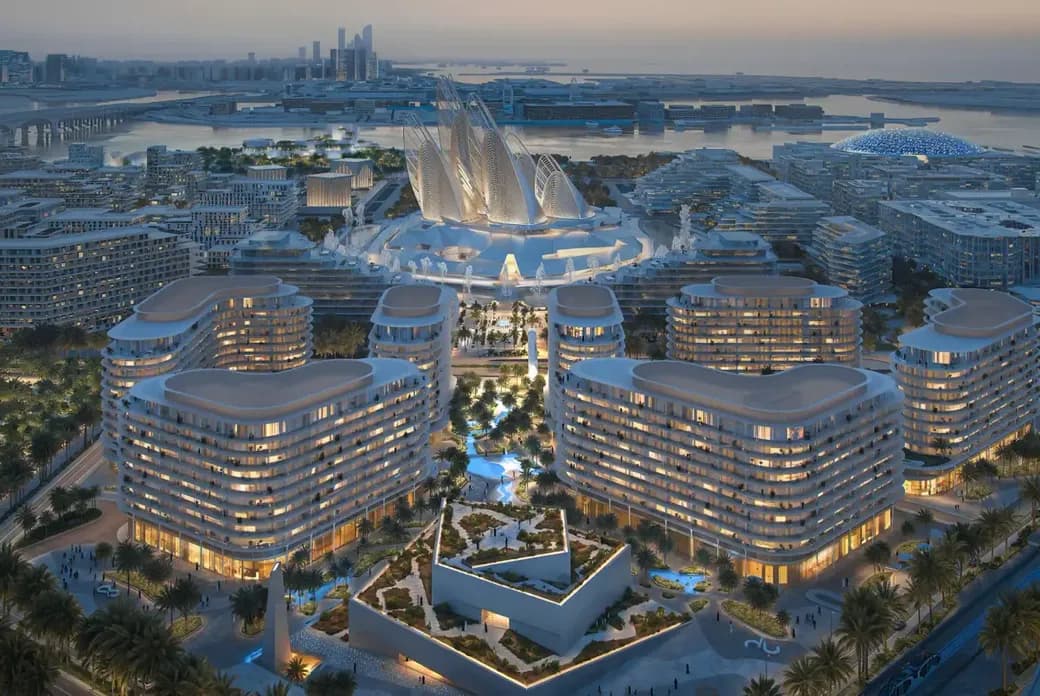 Aerial view of a futuristic cityscape at dusk with illuminated, curvy modern buildings, lush greenery, and waterfront in the background.