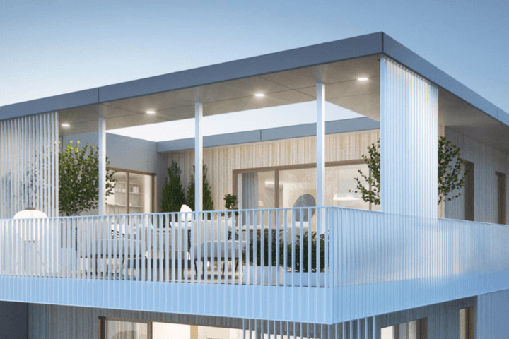 Immeuble d'appartements moderne avec un grand balcon doté de meubles blancs et de plantes, sous un toit gris.