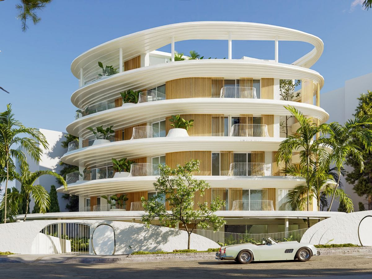White circular modern apartment building with layered curved terraces, palm trees and a pale green vintage convertible parked in front.
