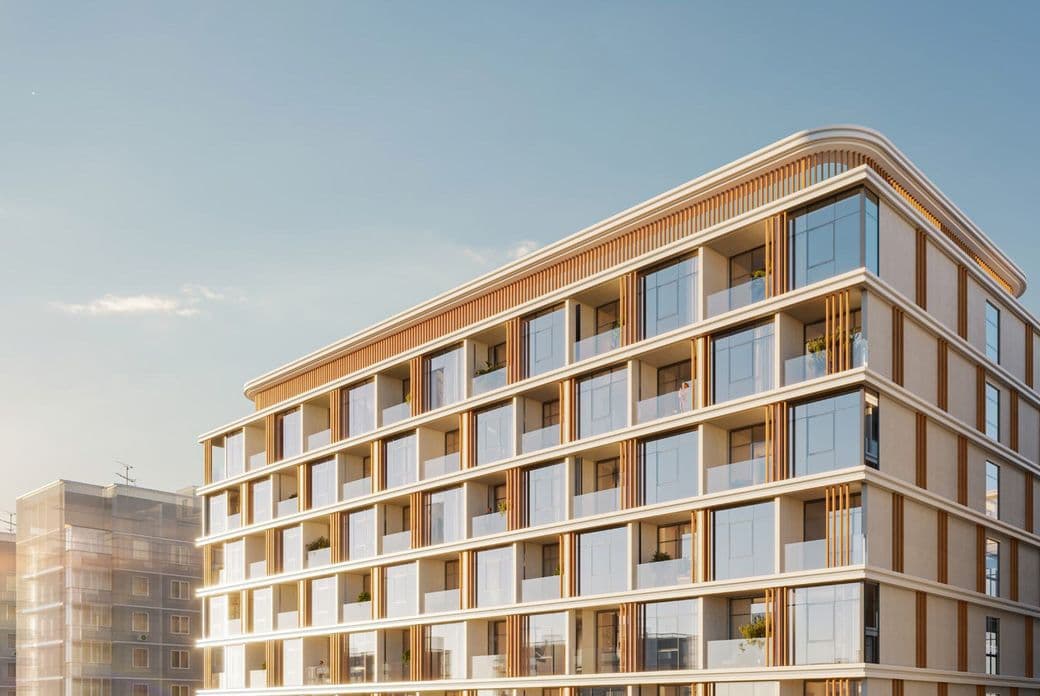 Modern building with glass balconies and brown accents under a clear blue sky, adjacent to other residential structures.