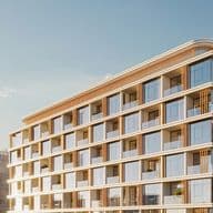 Modern building with glass balconies and brown accents under a clear blue sky, adjacent to other residential structures.