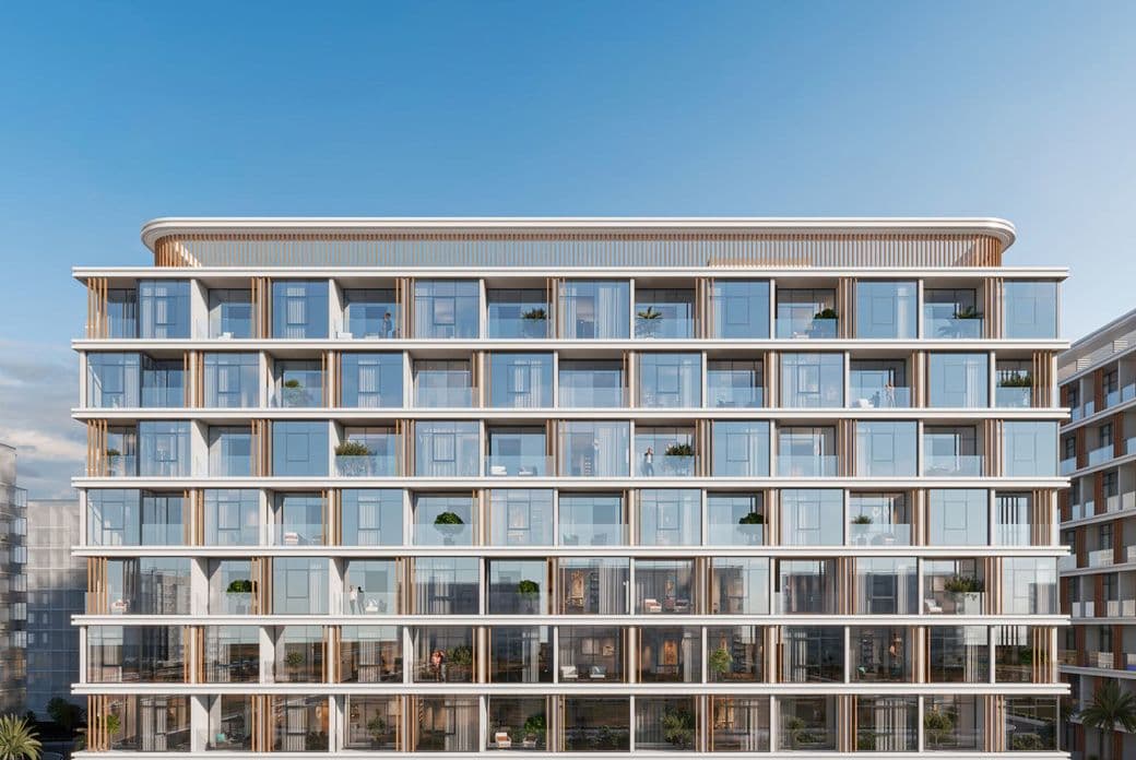 Modern multi-story glass building with balconies and plants, set against a clear blue sky.