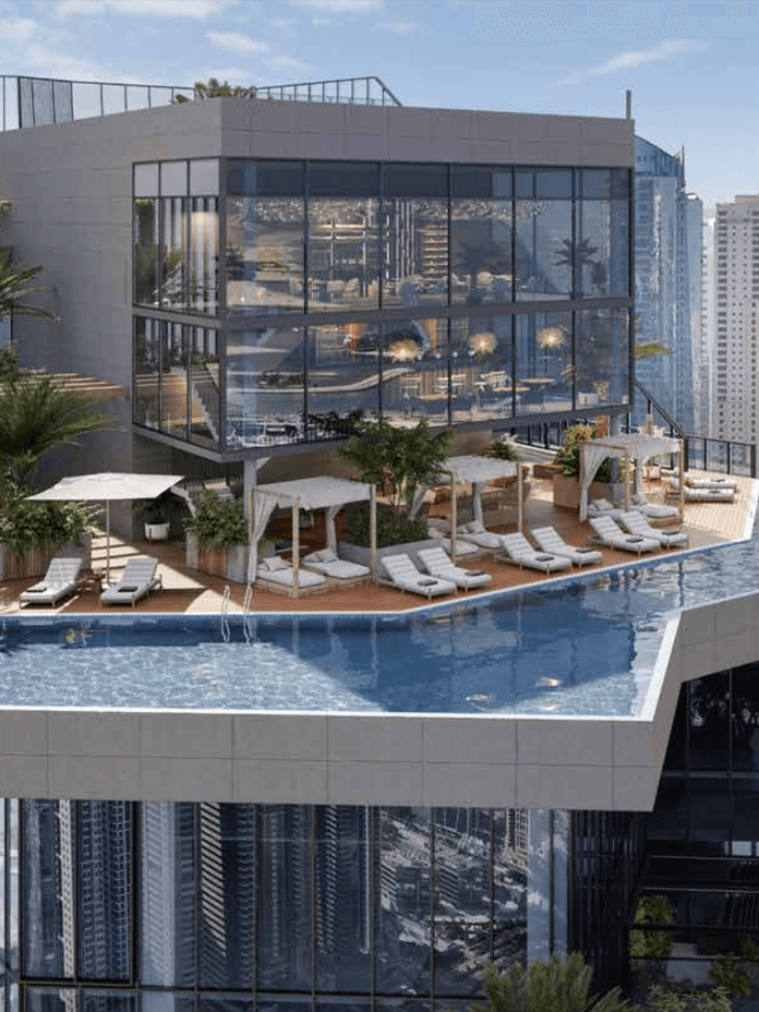 Rooftop with modern glass building, pool, lounge chairs, and greenery, overlooking a cityscape with tall skyscrapers in the background.