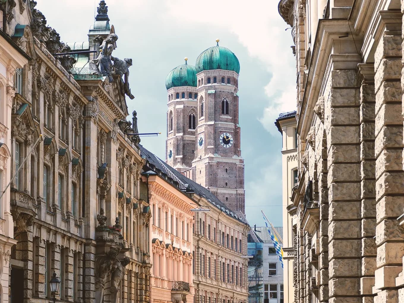 Historic old town street in Munich with a view of the Frauenkirche and its distinctive onion domes – a landmark and popular attraction in Munich’s city center.