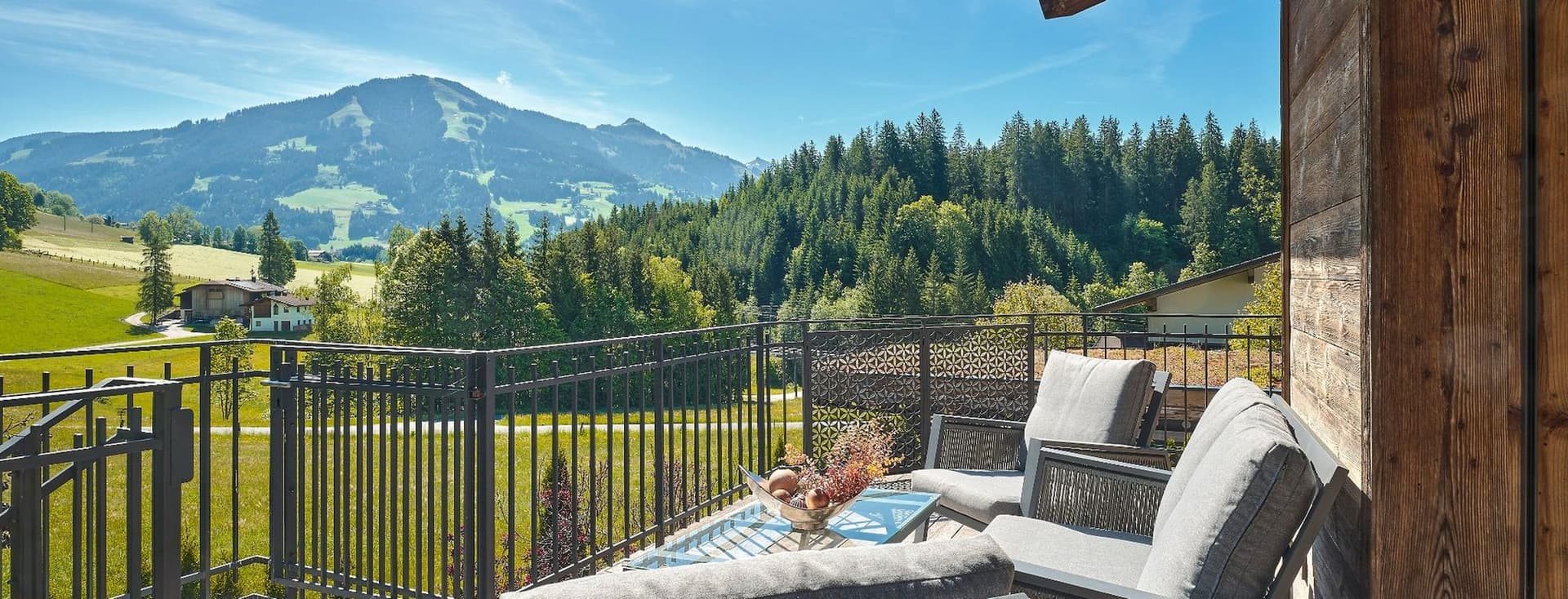 Terrasse eines hochwertigen Chalets mit Lounge-Möbeln und Blick auf die Kitzbüheler Berglandschaft