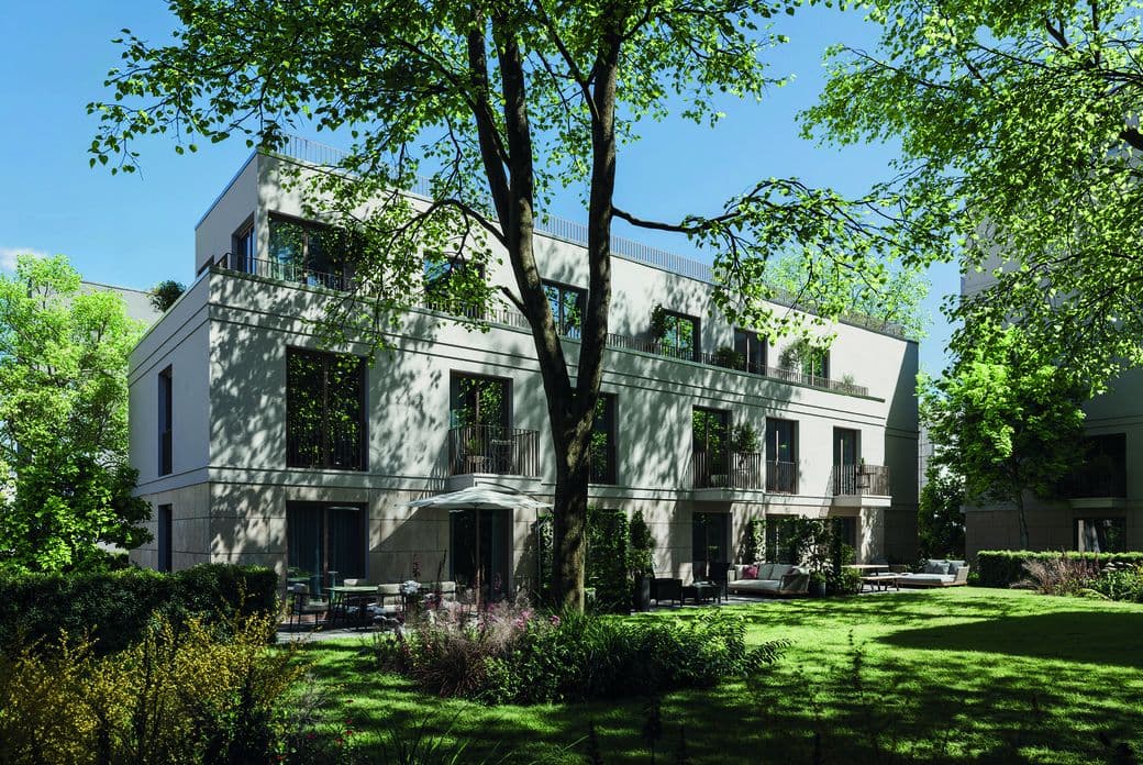 Modern white apartment building with multiple balconies, surrounded by lush green trees and a well-kept garden under a bright blue sky.