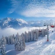 Chairlift over a snow-covered ski slope with Alpine panorama - the ideal location for ski in ski out properties with direct access to the slopes.