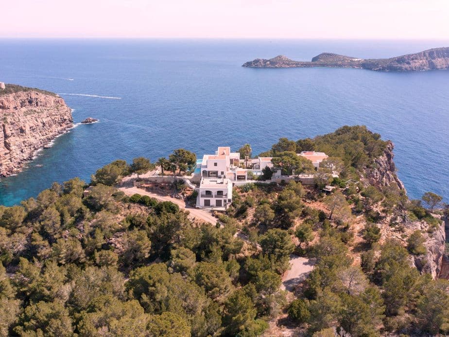 Aerial view of a villa on a wooded cliff in northern Ibiza with stunning sea views and unspoilt surroundings.