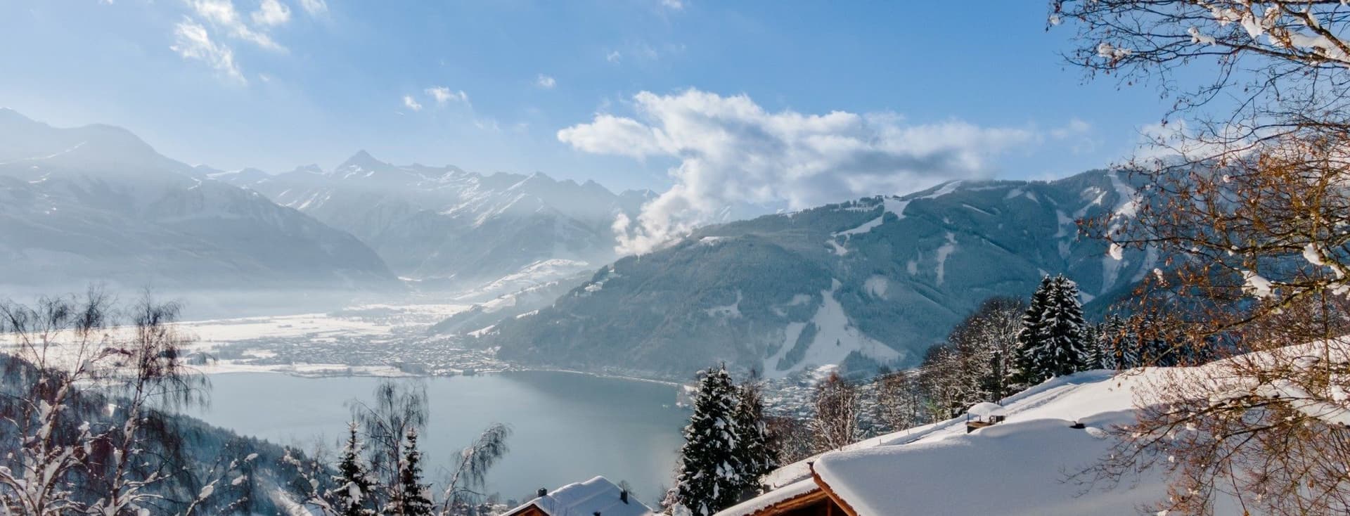 Panoramic photo of Zell am See with mountains and lake in winter.
