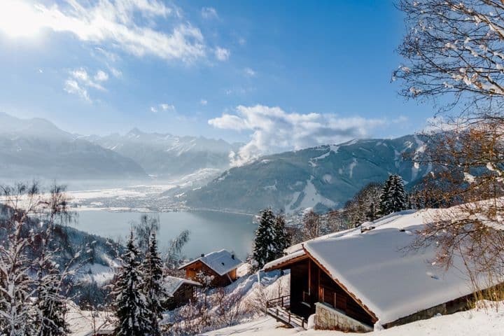 Panoramic photo of Zell am See with mountains and lake in winter.