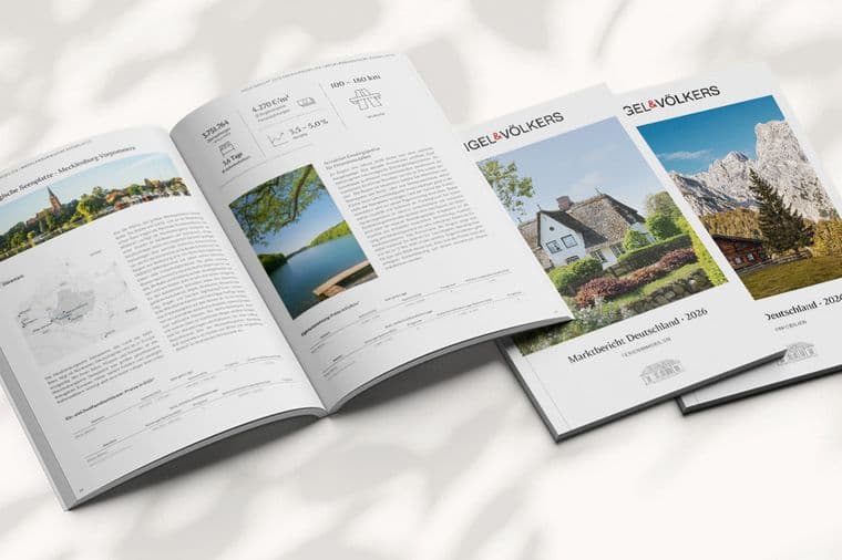 Geöffnete und geschlossene Immobilienbroschüren auf einem hellen Untergrund mit Schatten, mit Immobilienangeboten und Landschaftsfotos