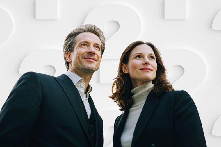 Ein Mann und eine Frau in Business-Kleidung blicken selbstbewusst nach oben, während sie vor einem Hintergrund aus großen weißen Fragezeichen stehen.