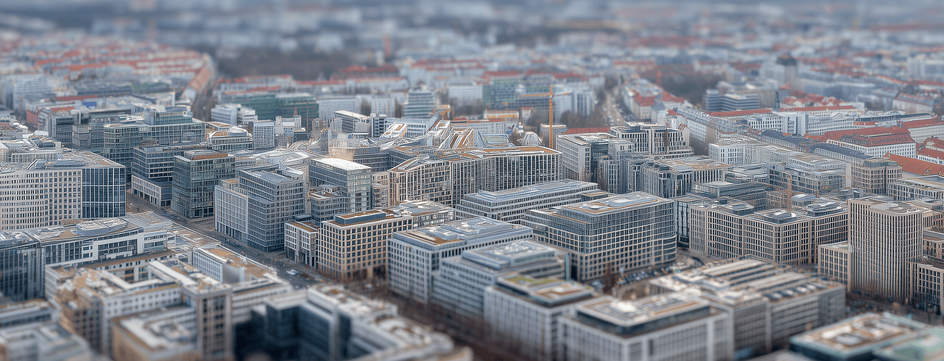 Aerial view of a cityscape with modern buildings, residential areas, and streets, showcasing a densely populated urban environment.