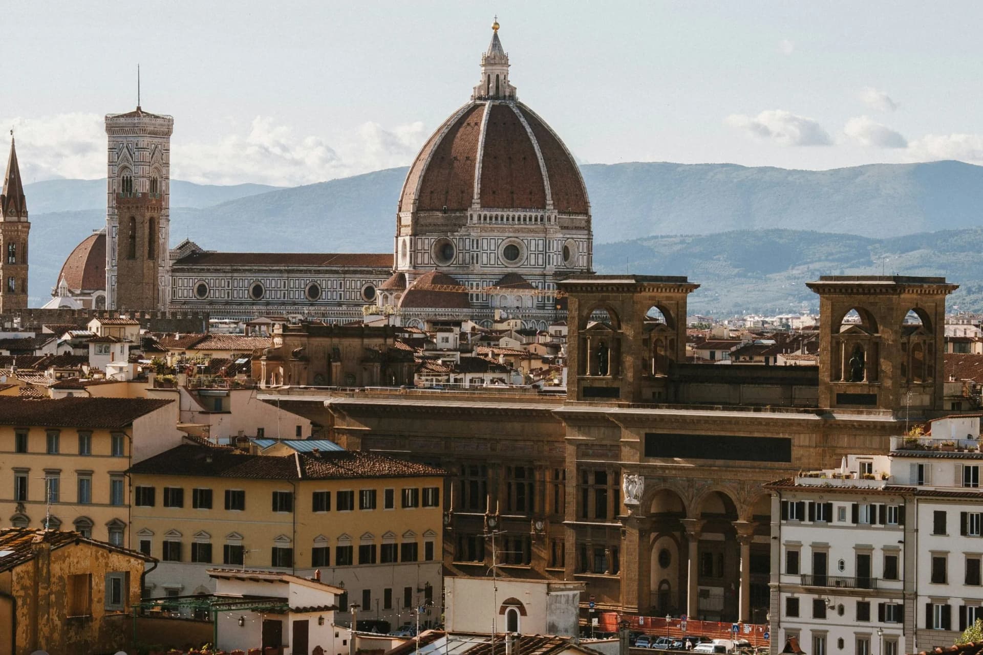 Florence cityscape with the iconic red-domed Florence Cathedral and Giotto's bell tower among historic buildings.