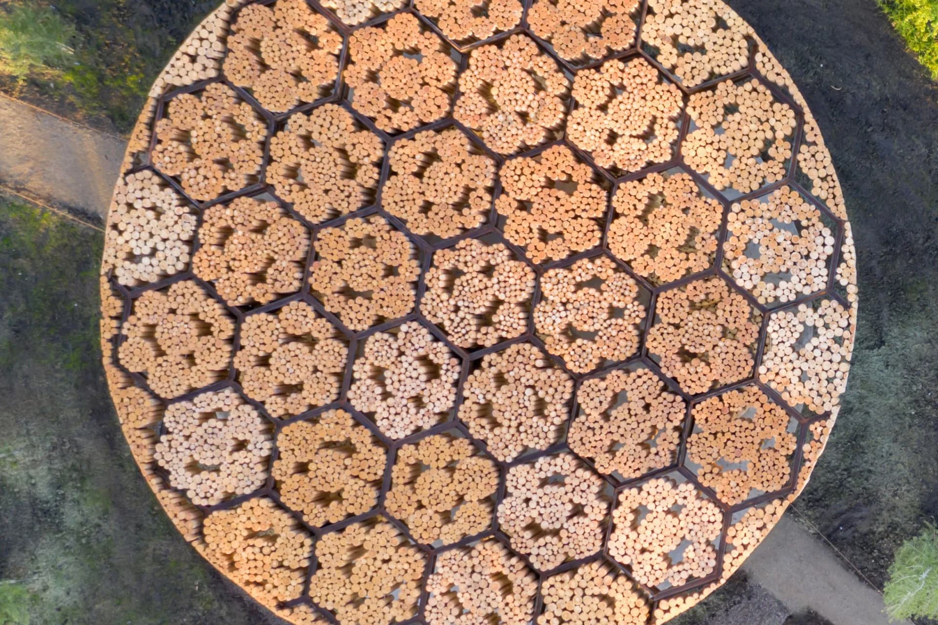 Aerial view of a circular wooden surface with a honeycomb pattern, filled with hexagonal cells made of small pieces of wood.