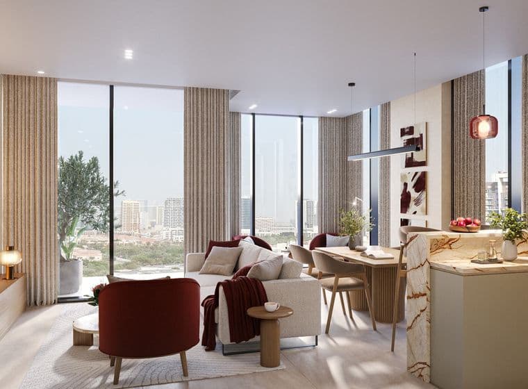 Modern living room with large windows, a cozy sofa, red chairs, and a marble kitchen island. Cityscape view in the background.