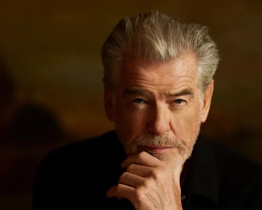 Close-up of a mature man with gray hair and beard, hand on chin, looking thoughtfully at the camera.