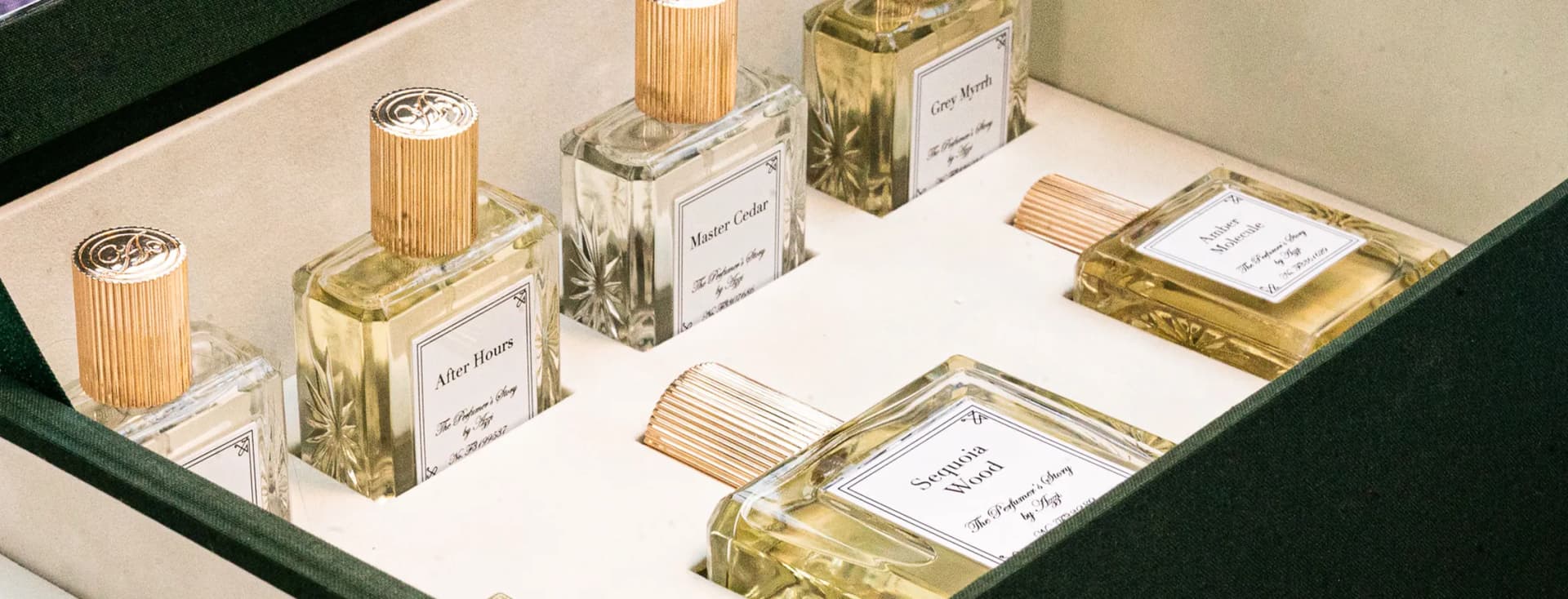 Una serie de frascos de perfume de cristal con tapones estriados en dorado expuestos en una vitrina; en las etiquetas se lee «Master Cedar», «Grey Myrrh» y «After Hours».