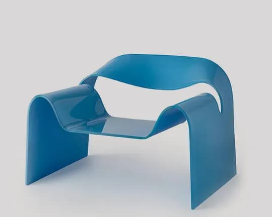 Blue sculptural plastic chair with curved loop sides and integrated seat, set against a light gray backdrop.