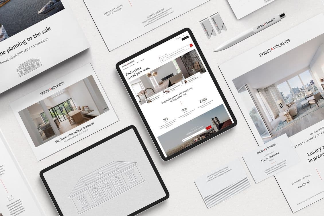 Engel & Völkers Marketingmaterialien: Tablet mit Website-Anzeige, Broschüren, Visitenkarten und ein Stift auf einer weißen Oberfläche.