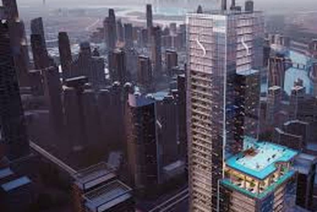 Aerial view of a cityscape featuring a tall skyscraper with a rooftop pool, surrounded by modern high-rise buildings, under a cloudy sky.
