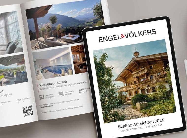 Ein Magazin und ein Tablet, auf denen Bilder von Luxus-Chalets zu sehen sind, daneben ein Cappuccino mit Latte-Art und ein Stylus auf einer hellgrauen Oberfläche.