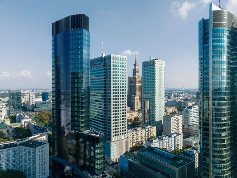 Cityscape with modern skyscrapers and historic buildings under a clear blue sky in Warsaw, Poland.