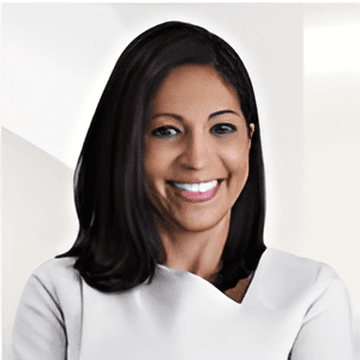 Smiling woman with shoulder-length dark hair wearing a white top against a light background.