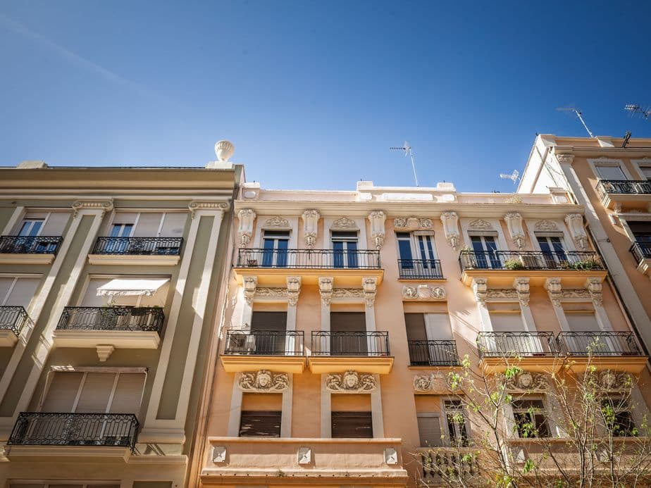 Ornate apartment buildings with balconies and decorative facades under a clear blue sky.