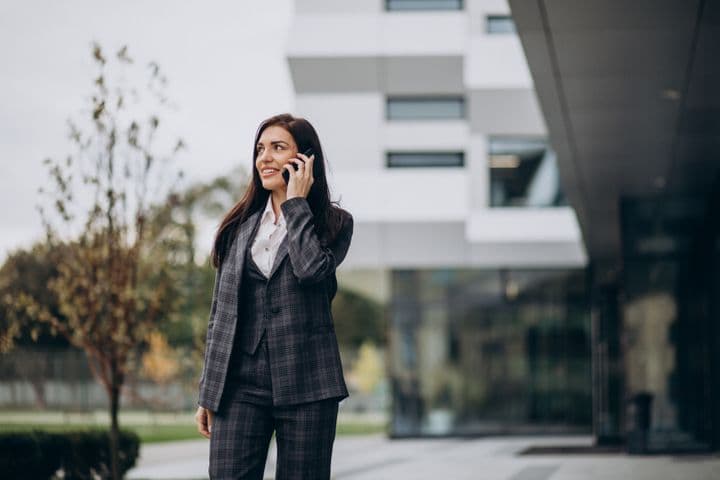 Agente immobiliare in un completo grigio parla al telefono fuori da una casa moderna
