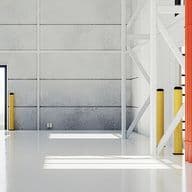 Interior of a spacious, empty warehouse with white walls, a concrete floor, and large doors, featuring yellow and red safety bollards.