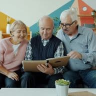 Tres personas de edad avanzada en una casa mirando un libro