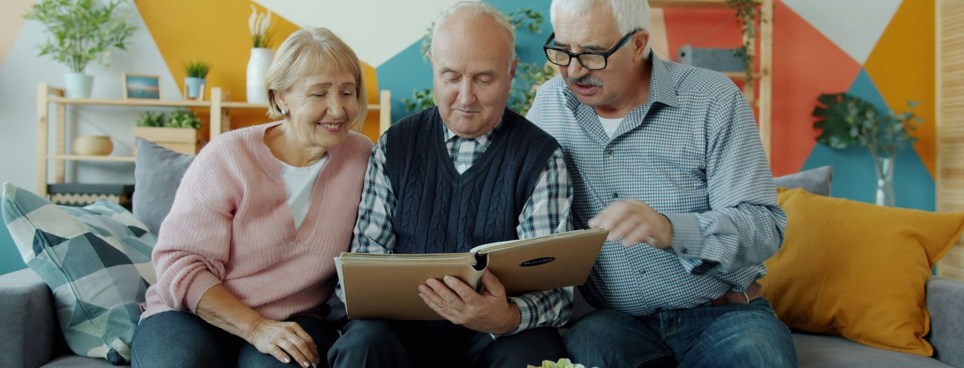 Tres personas de edad avanzada en una casa mirando un libro